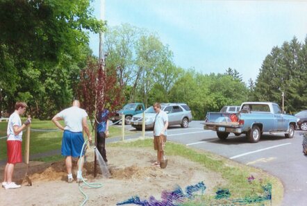 My dad filling the hole we dug for the tree with water.  Brett, Rob, and I stand around him holding shovels waiting.